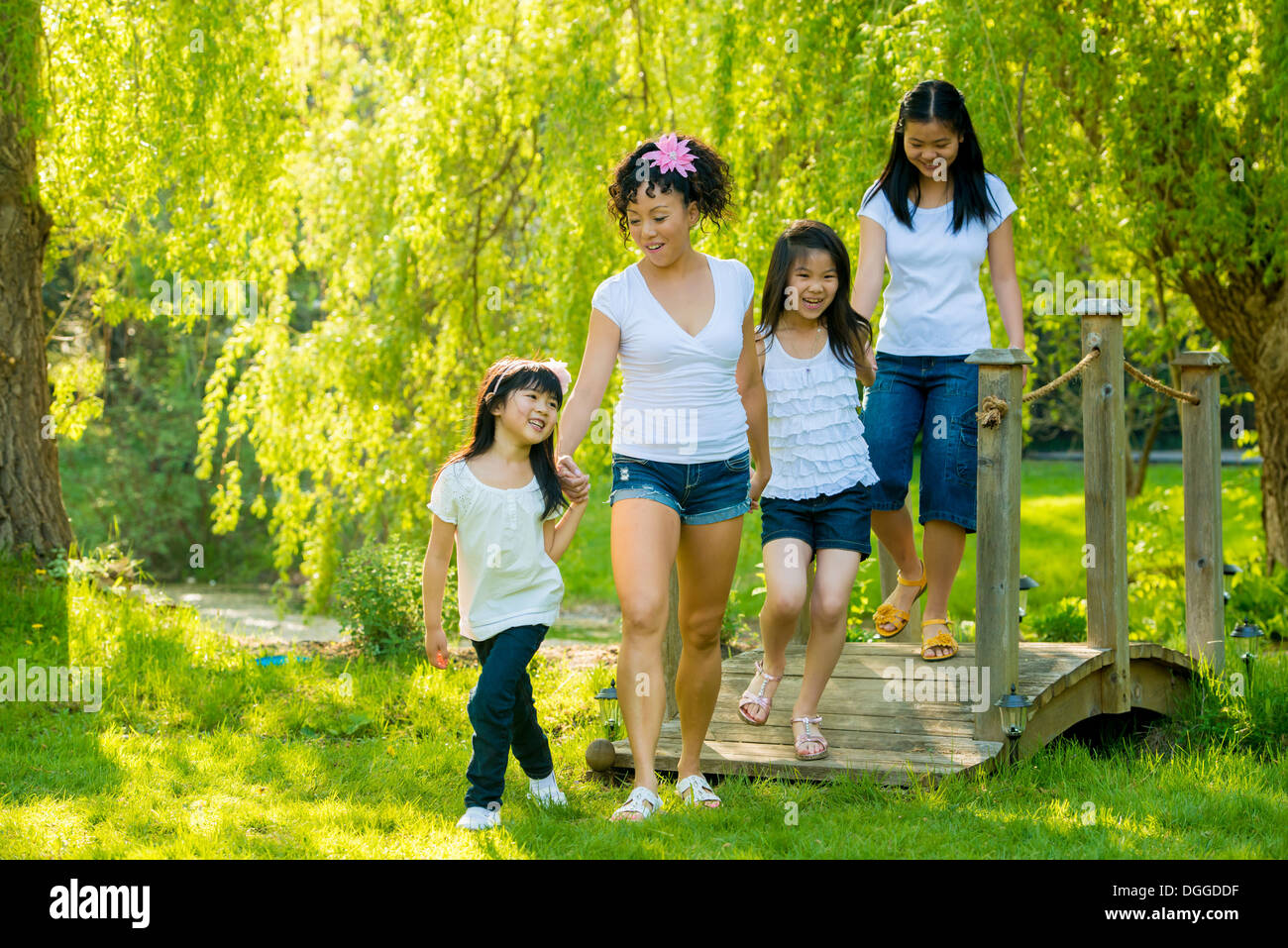 Femme et trois filles sur la passerelle en bois dans la région de park Banque D'Images