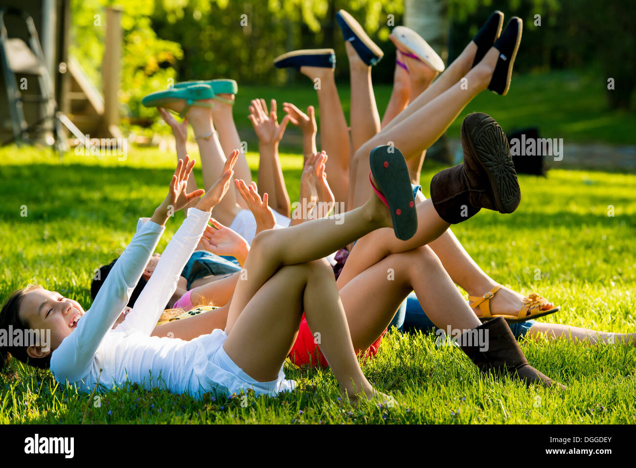 Girls lying on grass avec bras et jambes soulevées Banque D'Images