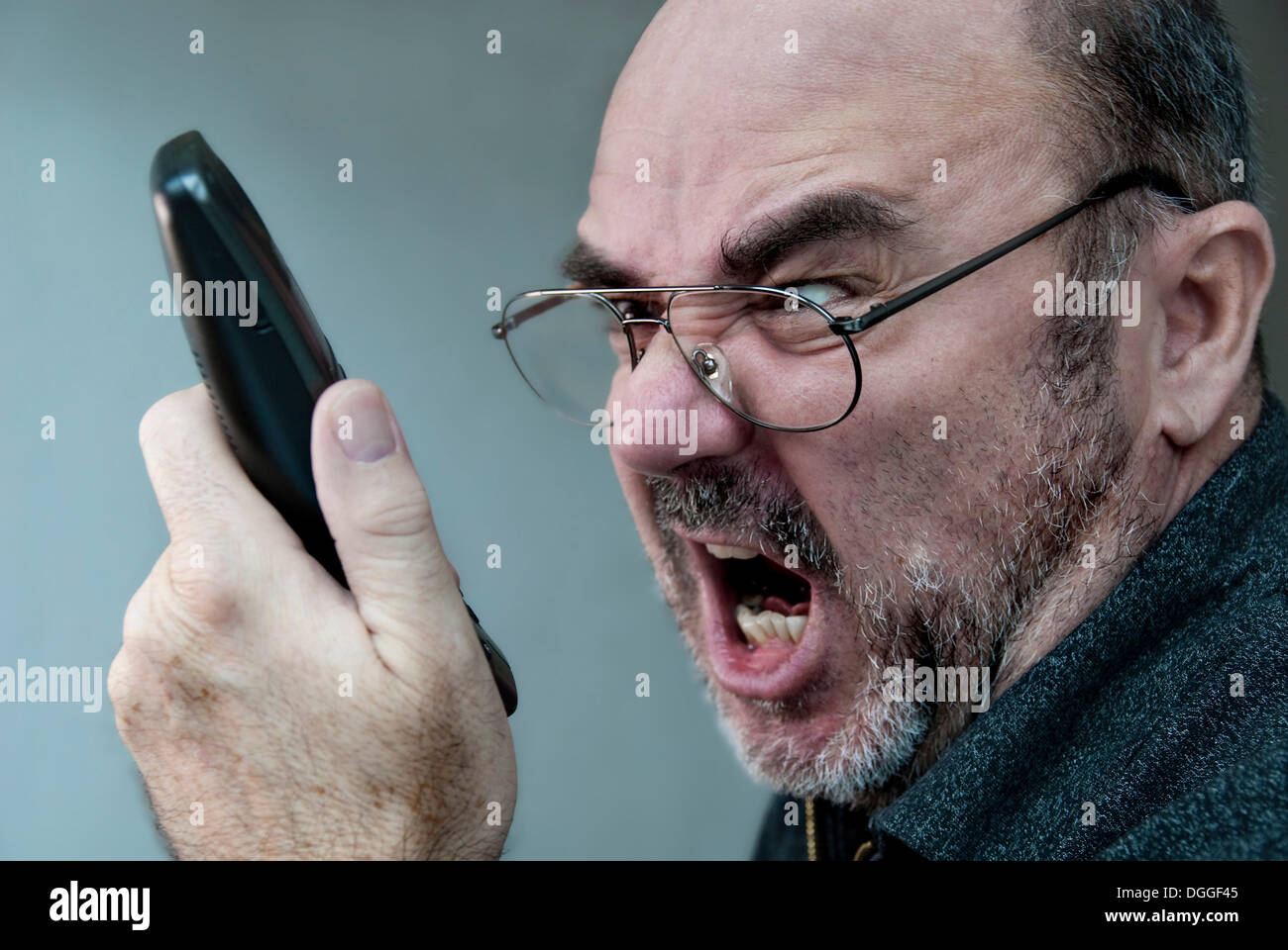 Homme en colère en criant dans un combiné téléphonique Banque D'Images
