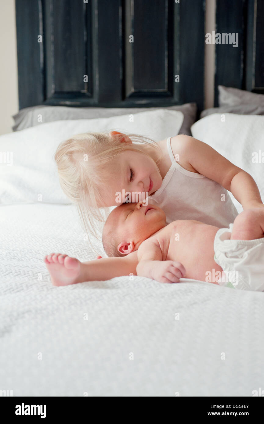 Girl sitting on bed with baby brother Banque D'Images