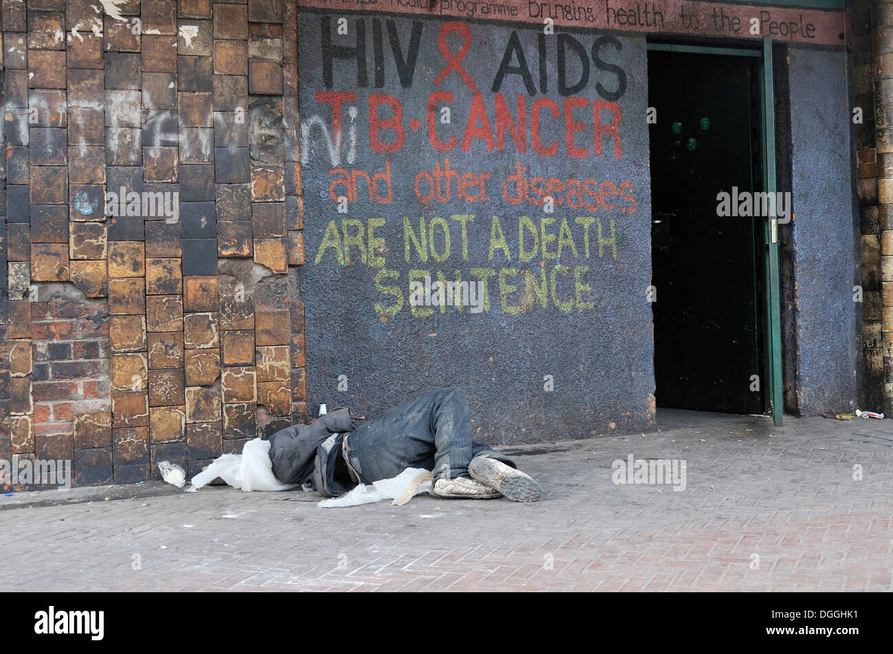 Sommeil de l'enfant de la rue en face de la porte portant le message, LE VIH ET LE SIDA, la tuberculose et le cancer autres disesases ne sont pas d'un décès Banque D'Images