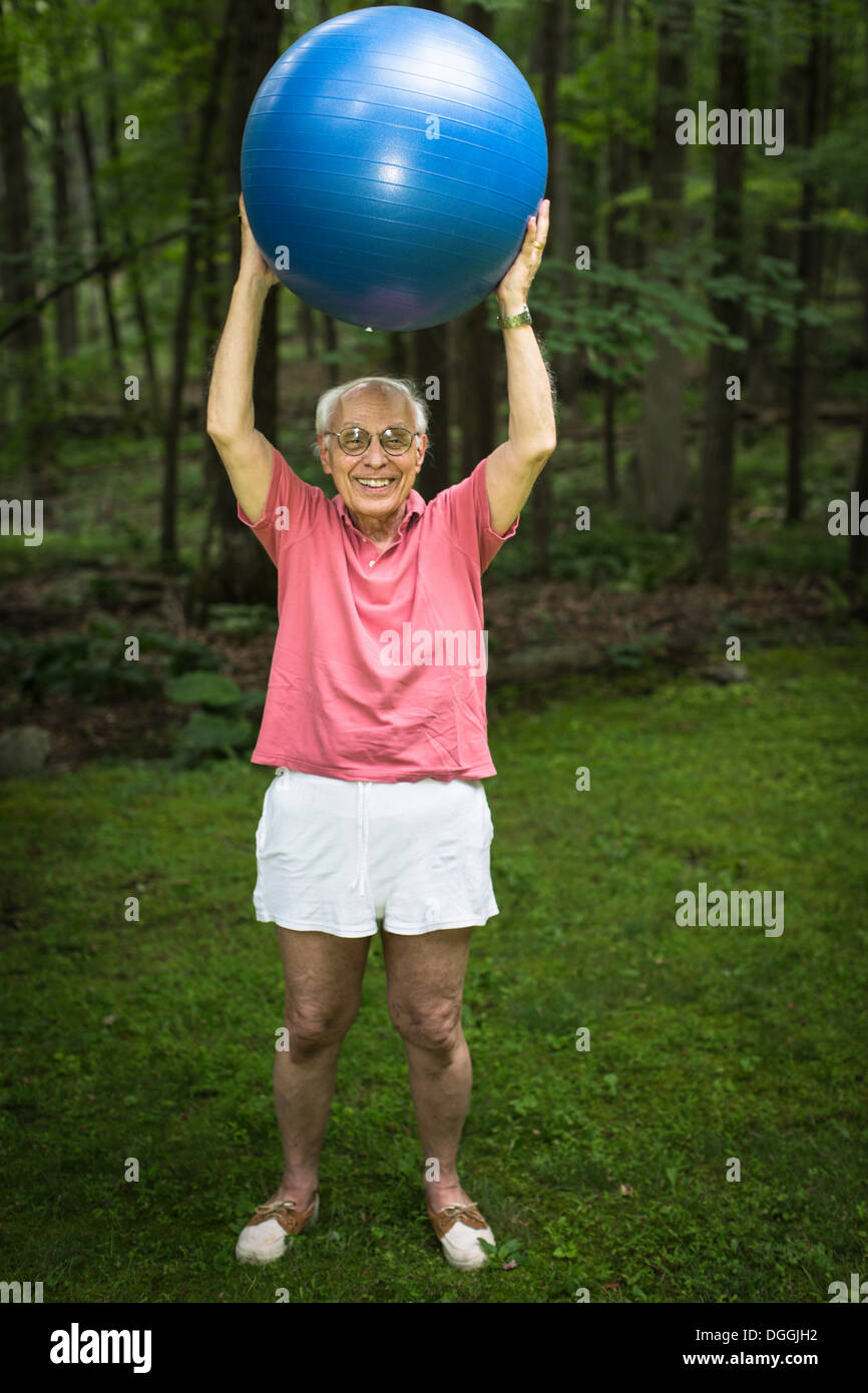 Senior man holding up exercise ball, portrait Banque D'Images