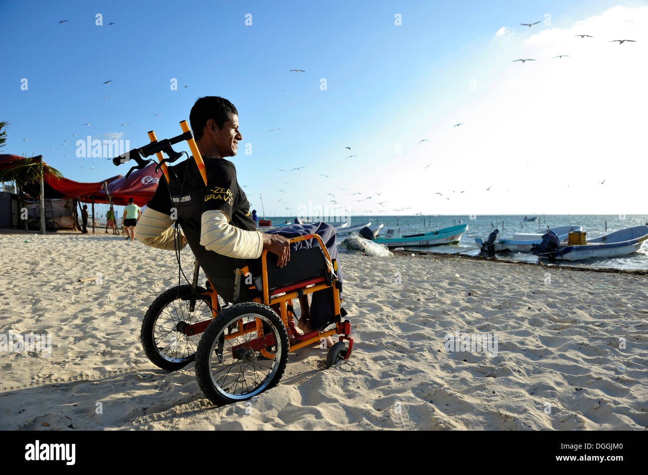 Pêcheur de homard qui souffrent de la maladie des caissons après un accident de plongée assis dans son fauteuil roulant à la plage, Cancun Banque D'Images