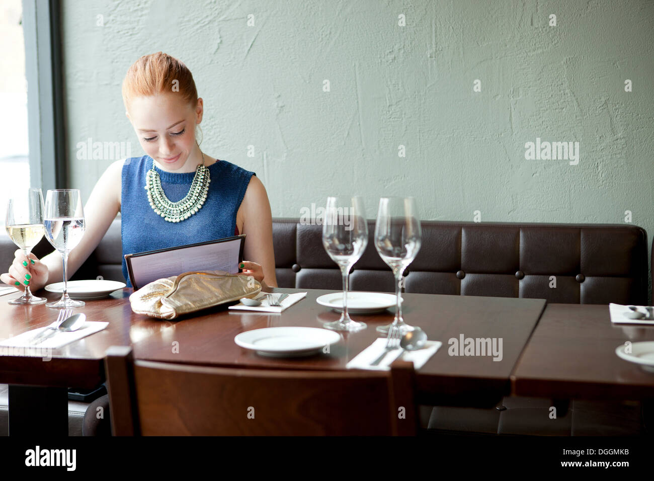 Jeune femme au restaurant, menu de lecture Banque D'Images