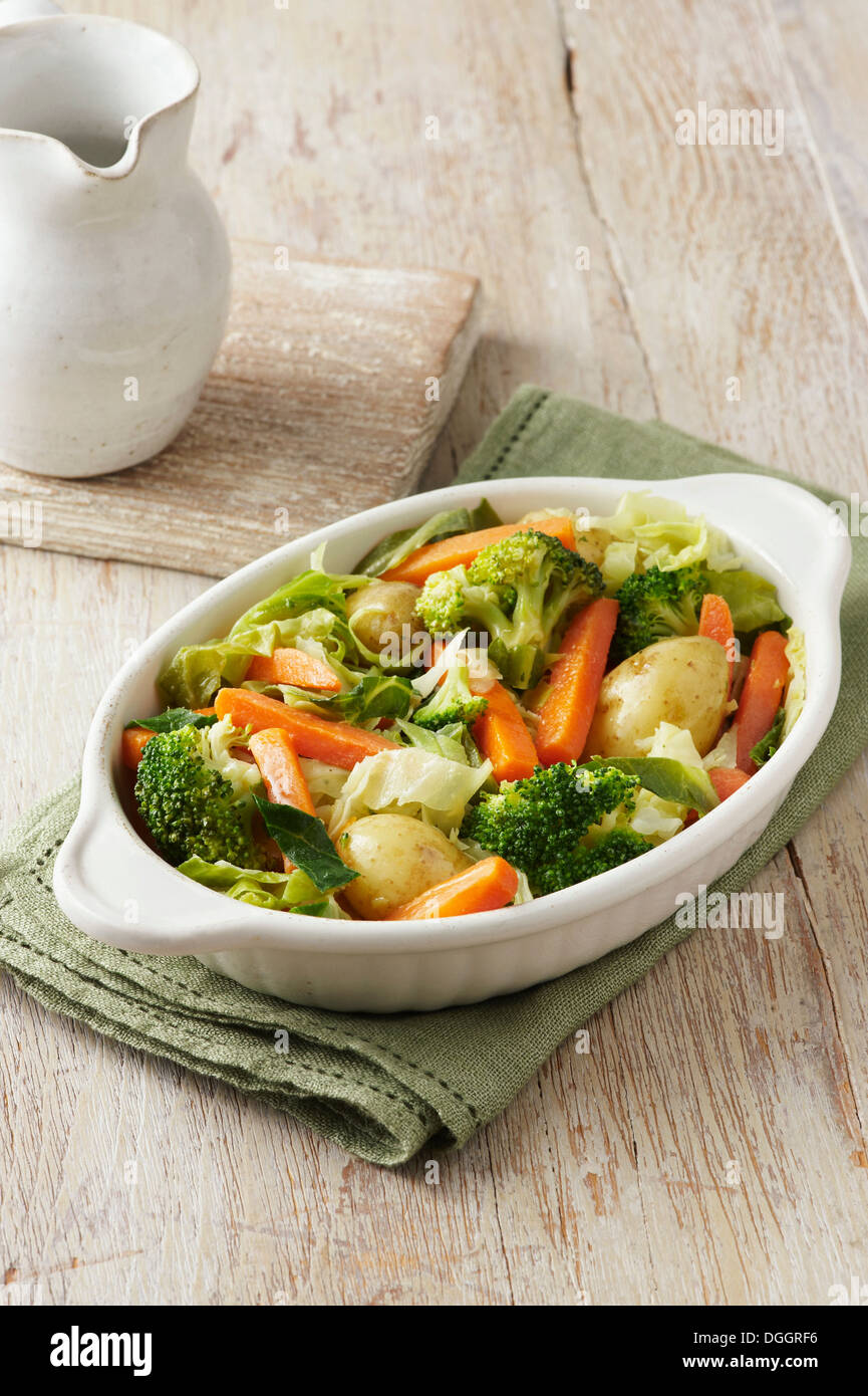 Sélection de légumes composé de brocoli, carottes, pommes de terre et le chou dans un plat de service blanc sur toile verte Banque D'Images