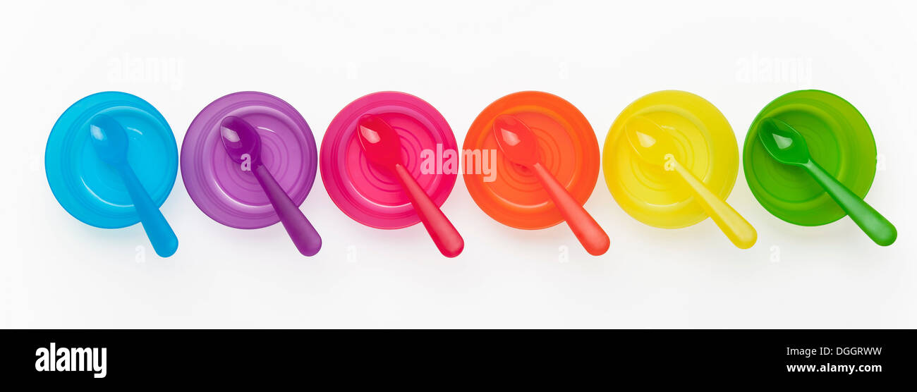 Cuillères en plastique coloré et bols dans une rangée Banque D'Images