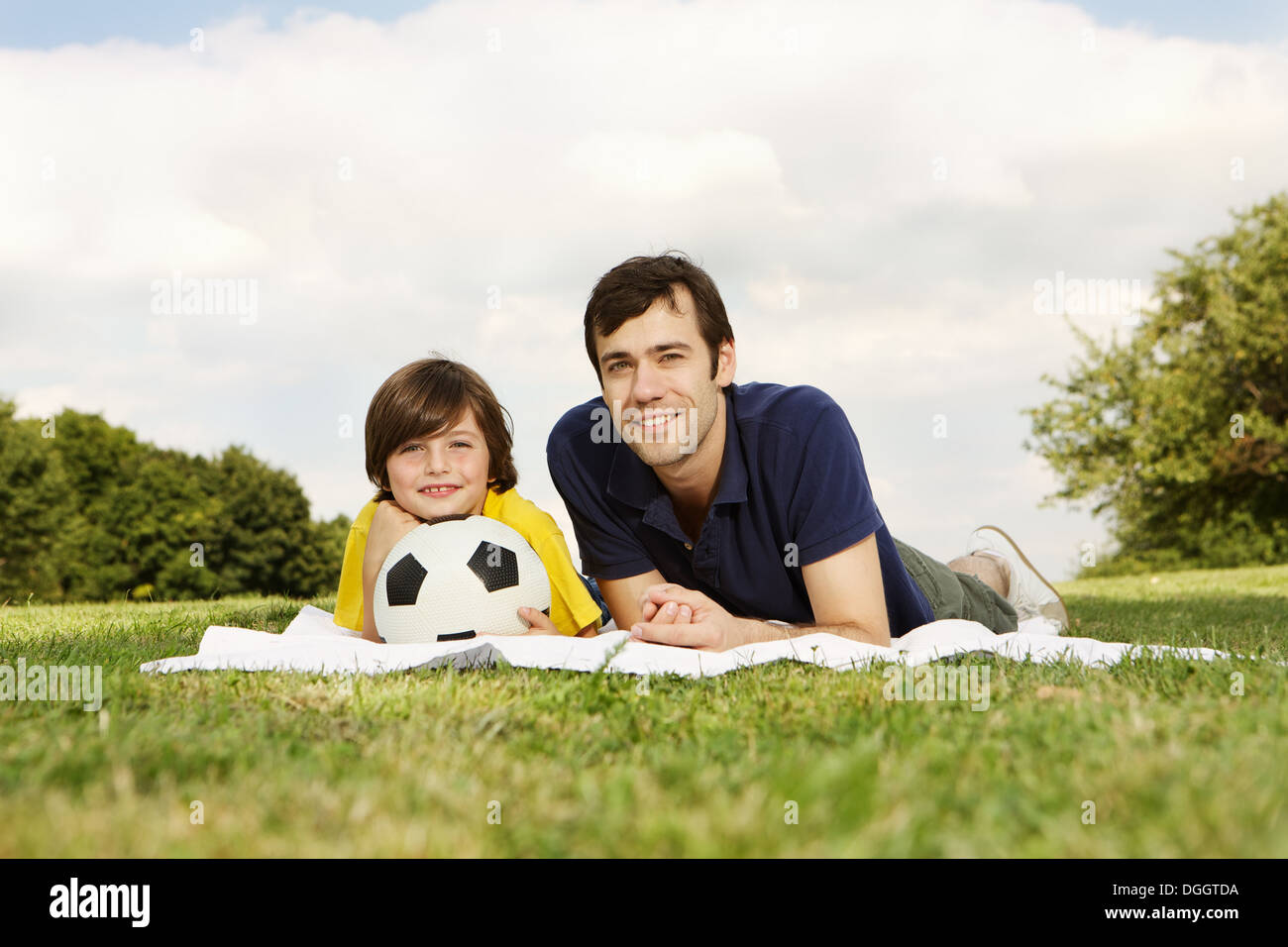 Père et fils lying on blanket avec football Banque D'Images