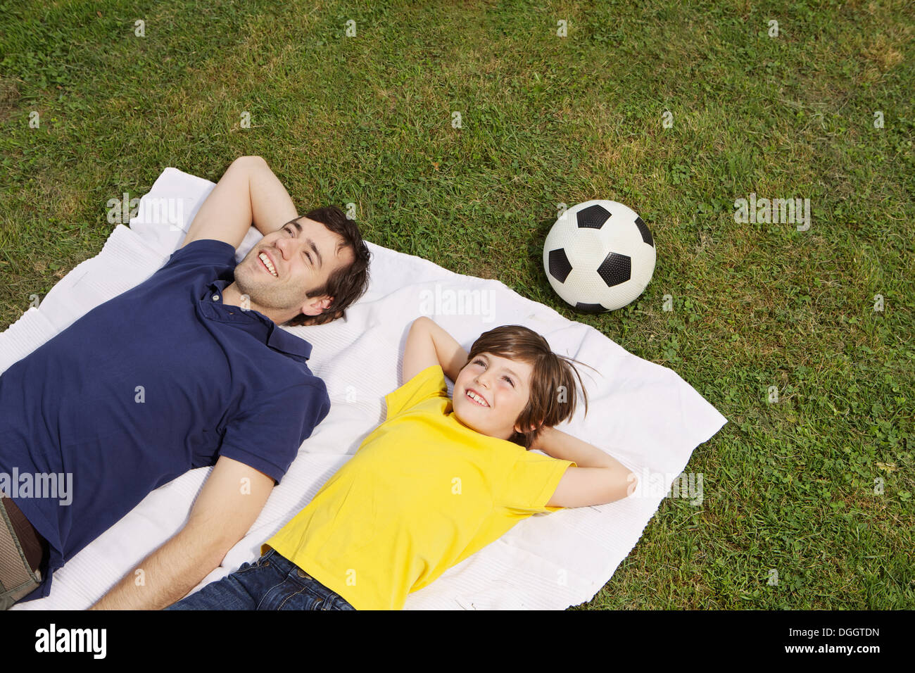 Père et fils lying on blanket avec football, high angle Banque D'Images