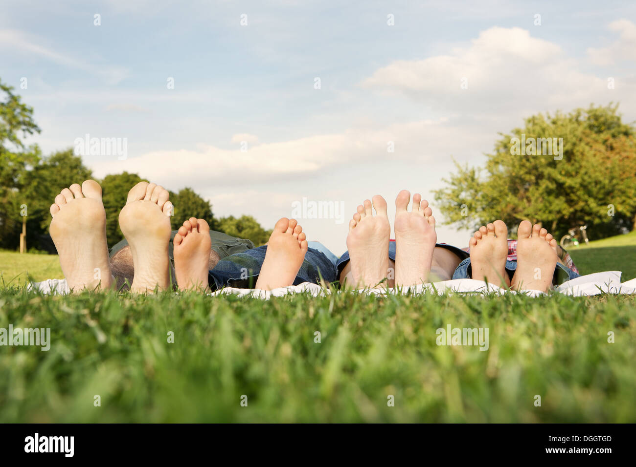 Famille avec deux enfants allongés sur l'herbe, l'accent sur pieds Banque D'Images