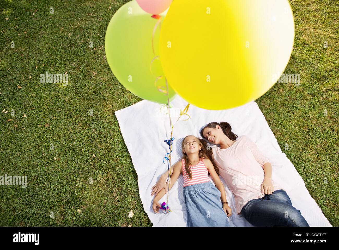 Mother and Daughter lying on blanket holding balloons, high angle Banque D'Images