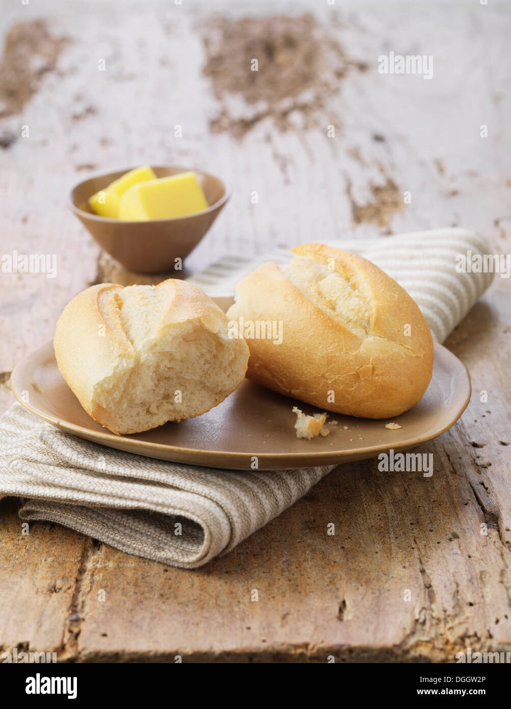 Petit pain blanc avec du beurre sur une plaque en céramique et serviette à rayures Banque D'Images