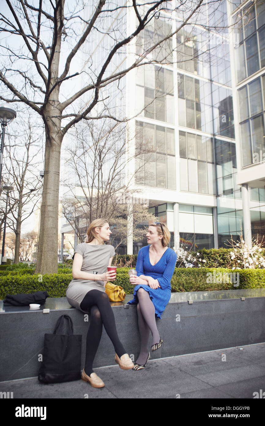 Businesswomen sitting on wall pour pause café Banque D'Images