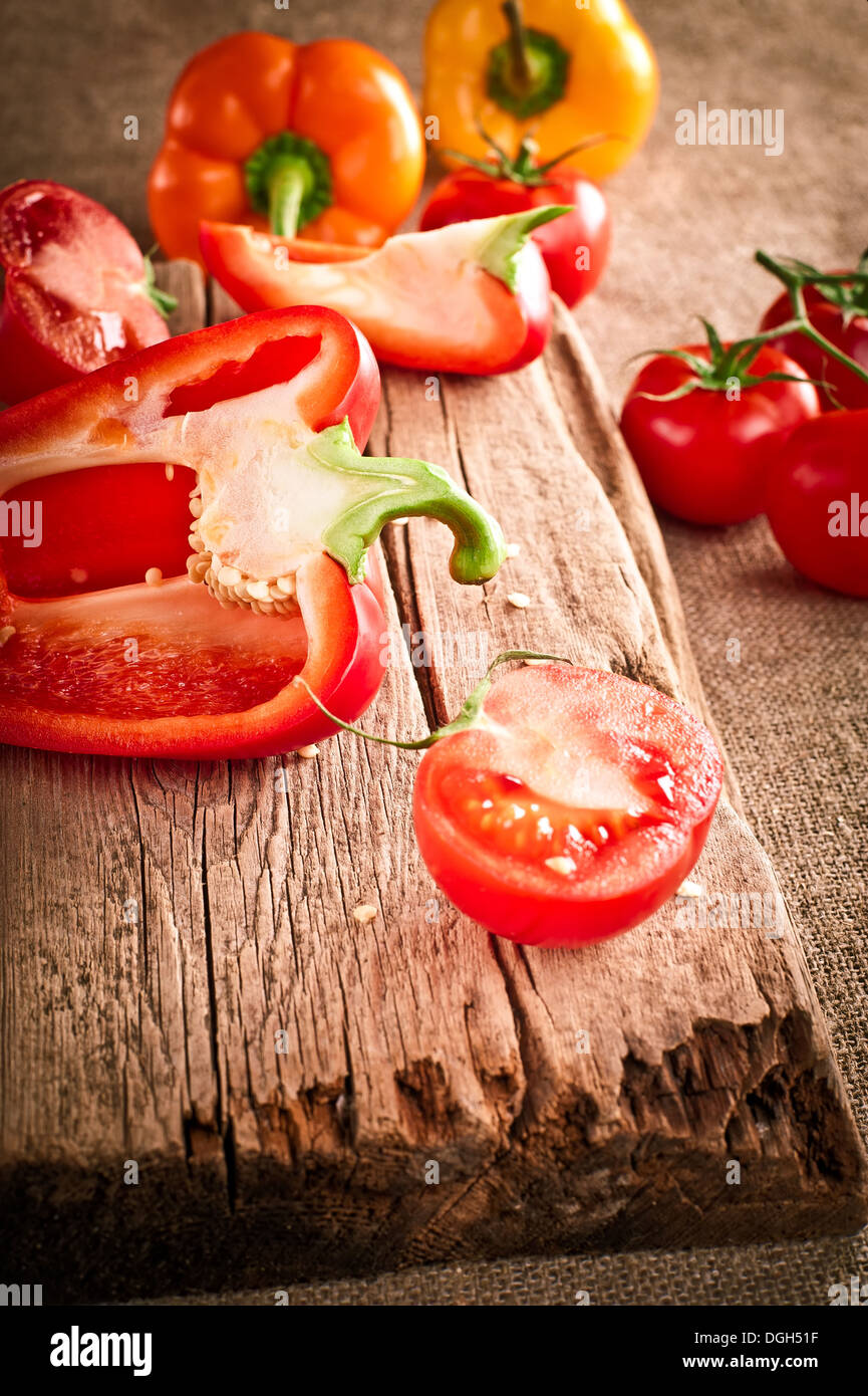Les tomates fraîches et le paprika, à la planche à découper en bois sur toile cirée. Image dans un style vintage Banque D'Images