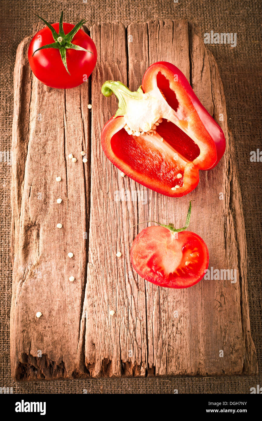 Les tomates fraîches et le paprika, à la planche à découper en bois sur toile cirée. Image dans un style vintage Banque D'Images