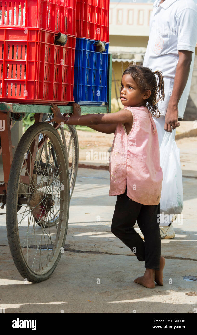 Basse caste indien Girl standing by un tricycle de boîtes contenant des paquets de nourriture. Puttaparthi, Andhra Pradesh, Inde Banque D'Images