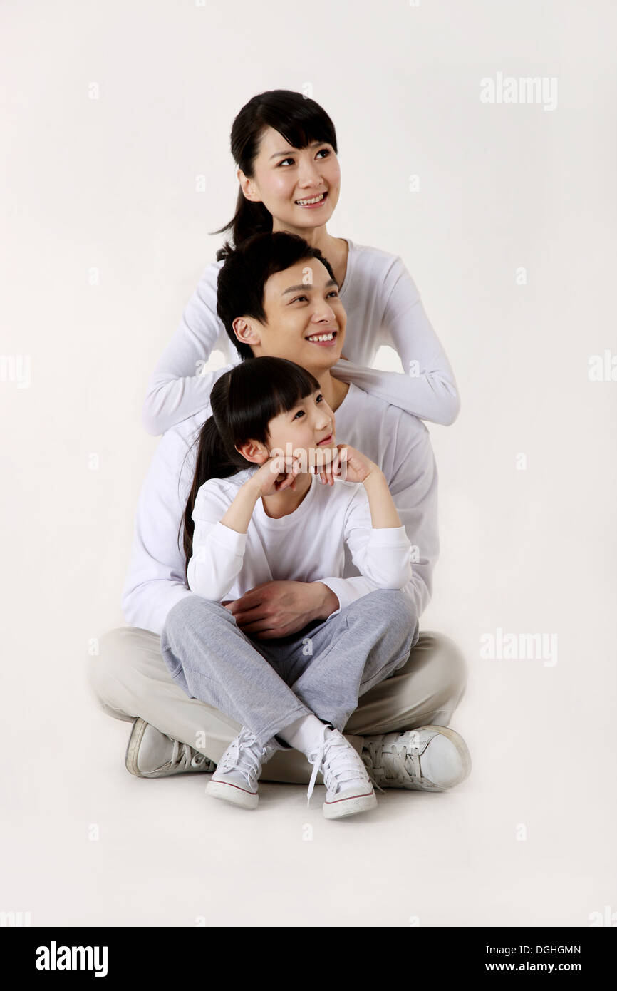 La famille de l'Asie de l'est avec un enfant assis en ligne sur le plancher avec le sourire Banque D'Images