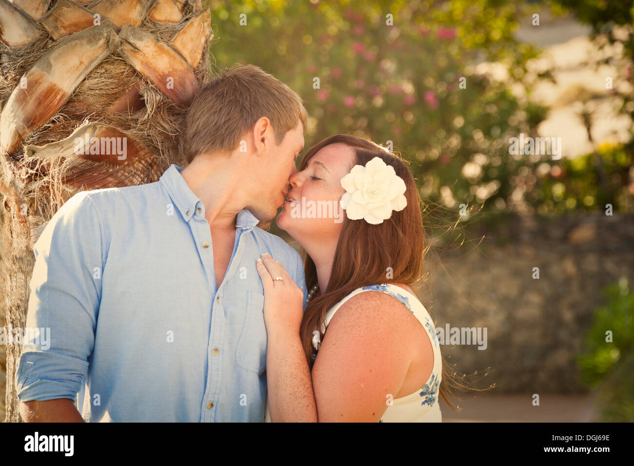 Couple espiègle et taquine en sous jardin tropical avec des palmiers et de fleurs, à la fin de soir chaud, lumière douce. Banque D'Images