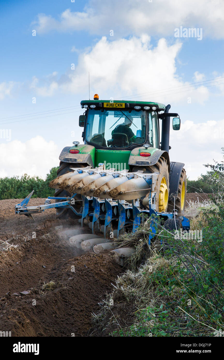 Le labour avec un tracteur John Deere et charrue réversible à North Norfolk. Banque D'Images