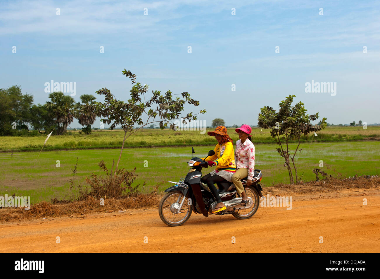 Deux femmes à cheval sur une moto sur une route de campagne, au Cambodge Banque D'Images