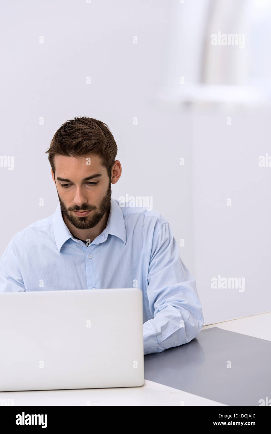 Jeune homme assis derrière laptop in office Banque D'Images