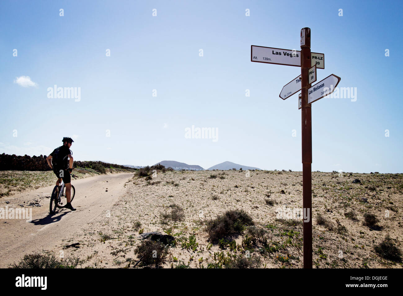 Man mountain biking, Lanzarote sign post passé Banque D'Images