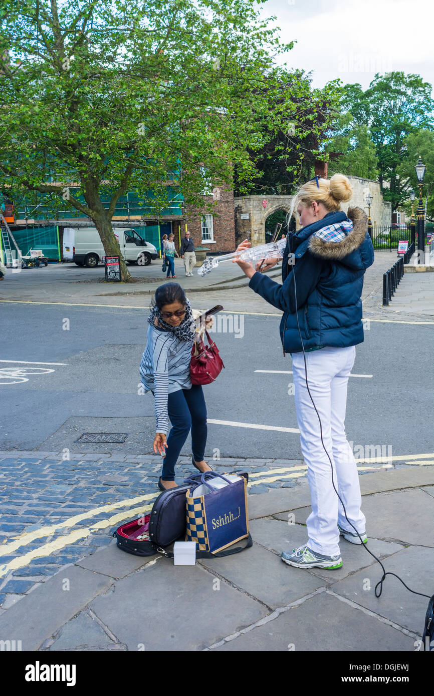 Un touriste faisant un don à un musicien ambulant. Banque D'Images
