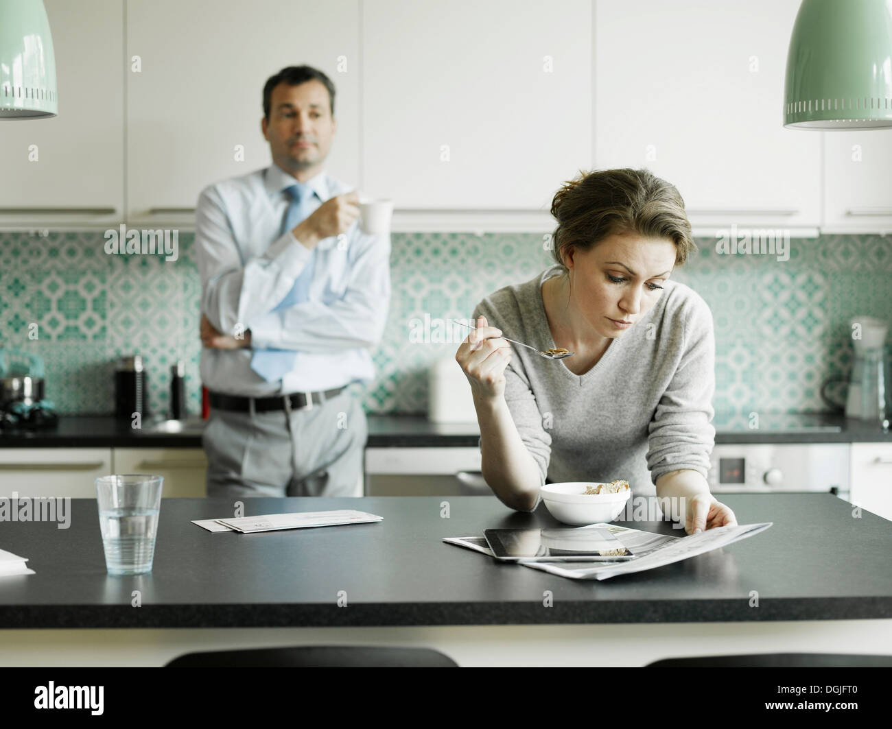 Mid adult woman reading document pendant le petit-déjeuner dans la cuisine Banque D'Images