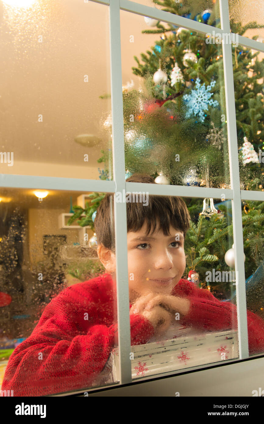 Garçon regardant fixement la fenêtre de la veille de Noël Banque D'Images