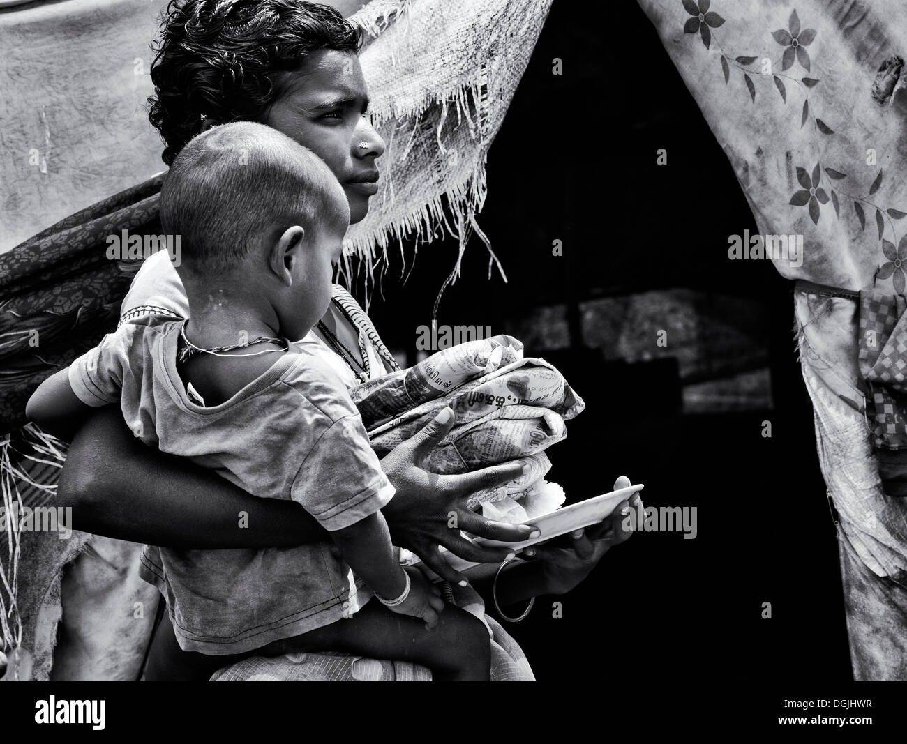 Basse caste adolescente Indienne et son fils qui reçoivent gratuitement de la nourriture à l'extérieur de son bender. L'Andhra Pradesh, Inde. Monochrome Banque D'Images