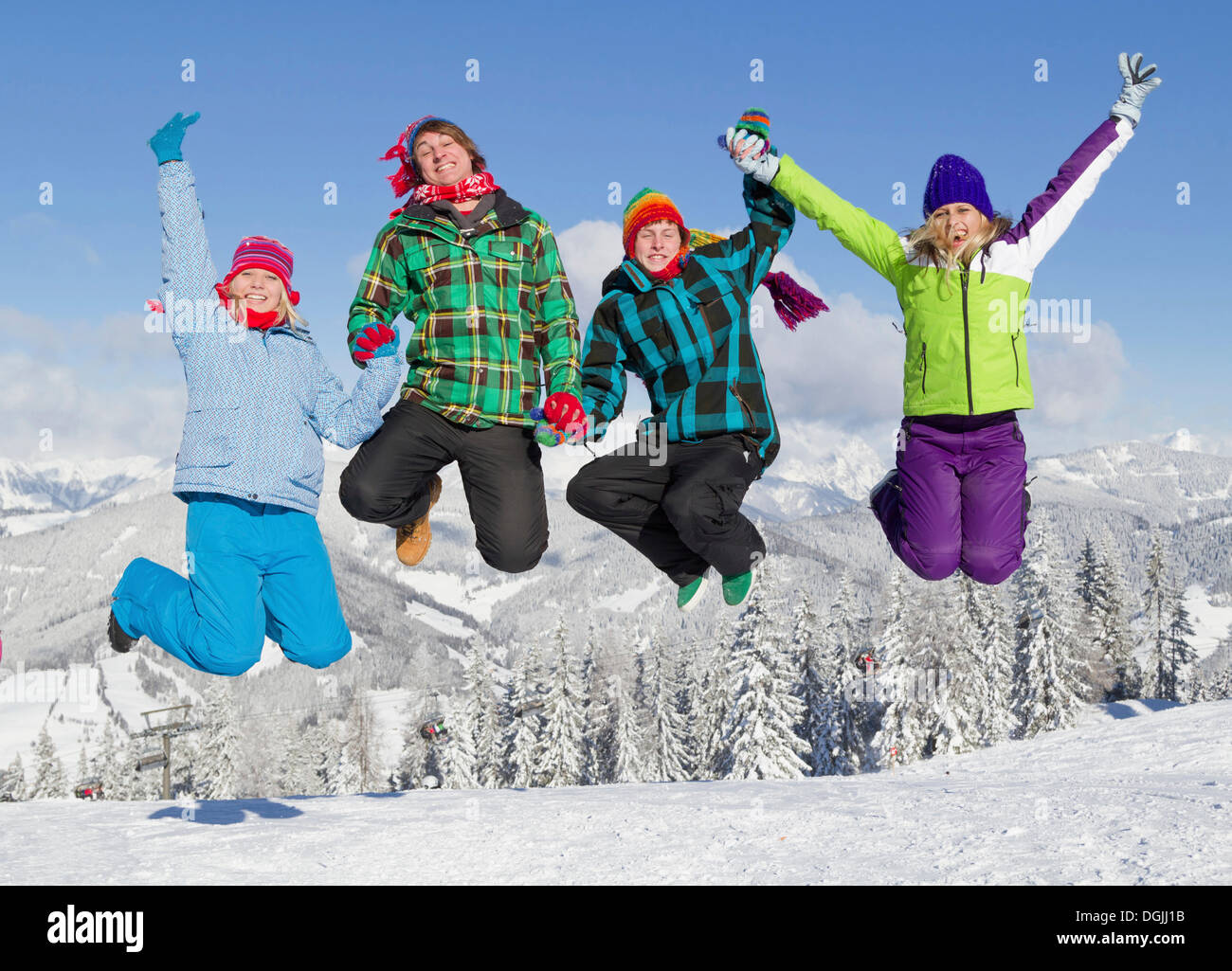 Groupe de jeunes gens sautant sur une pente de ski, Salzburger Land, Flachau, Tyrol, Autriche Banque D'Images