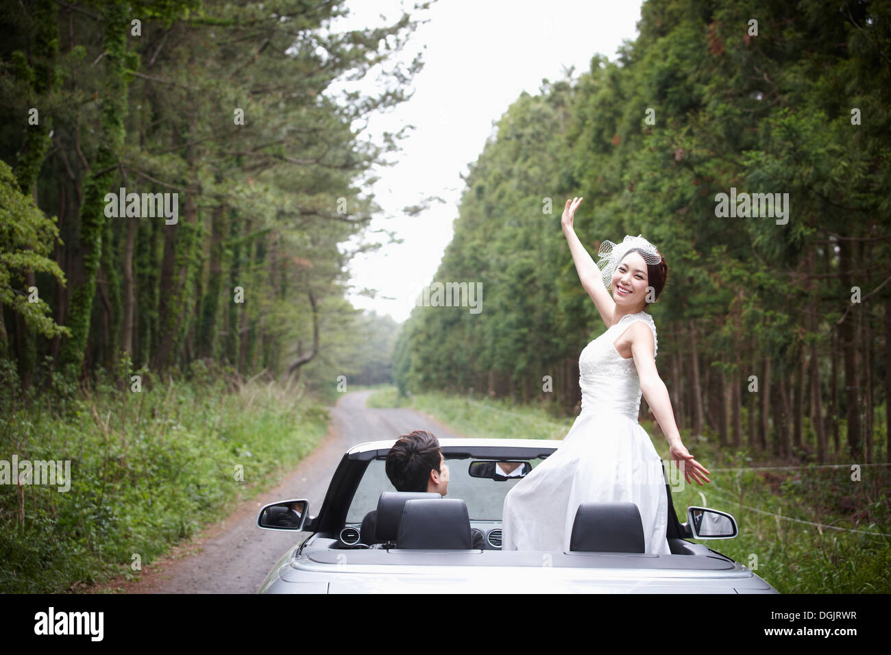 Les nouveaux mariés au volant d'une voiture décapotable Banque D'Images
