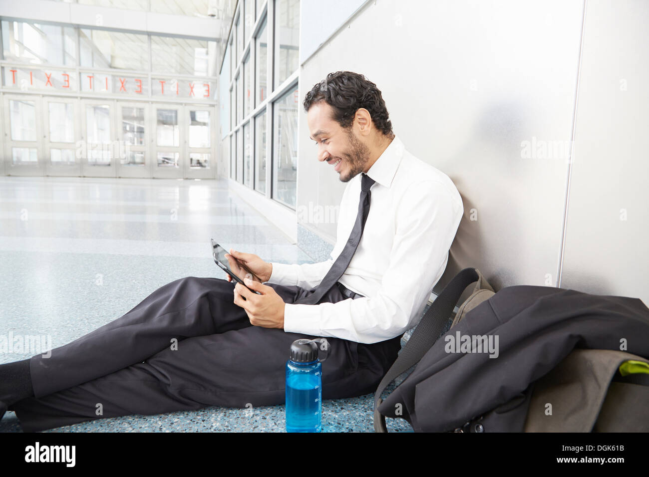 Businessman sitting on floor using digital tablet Banque D'Images