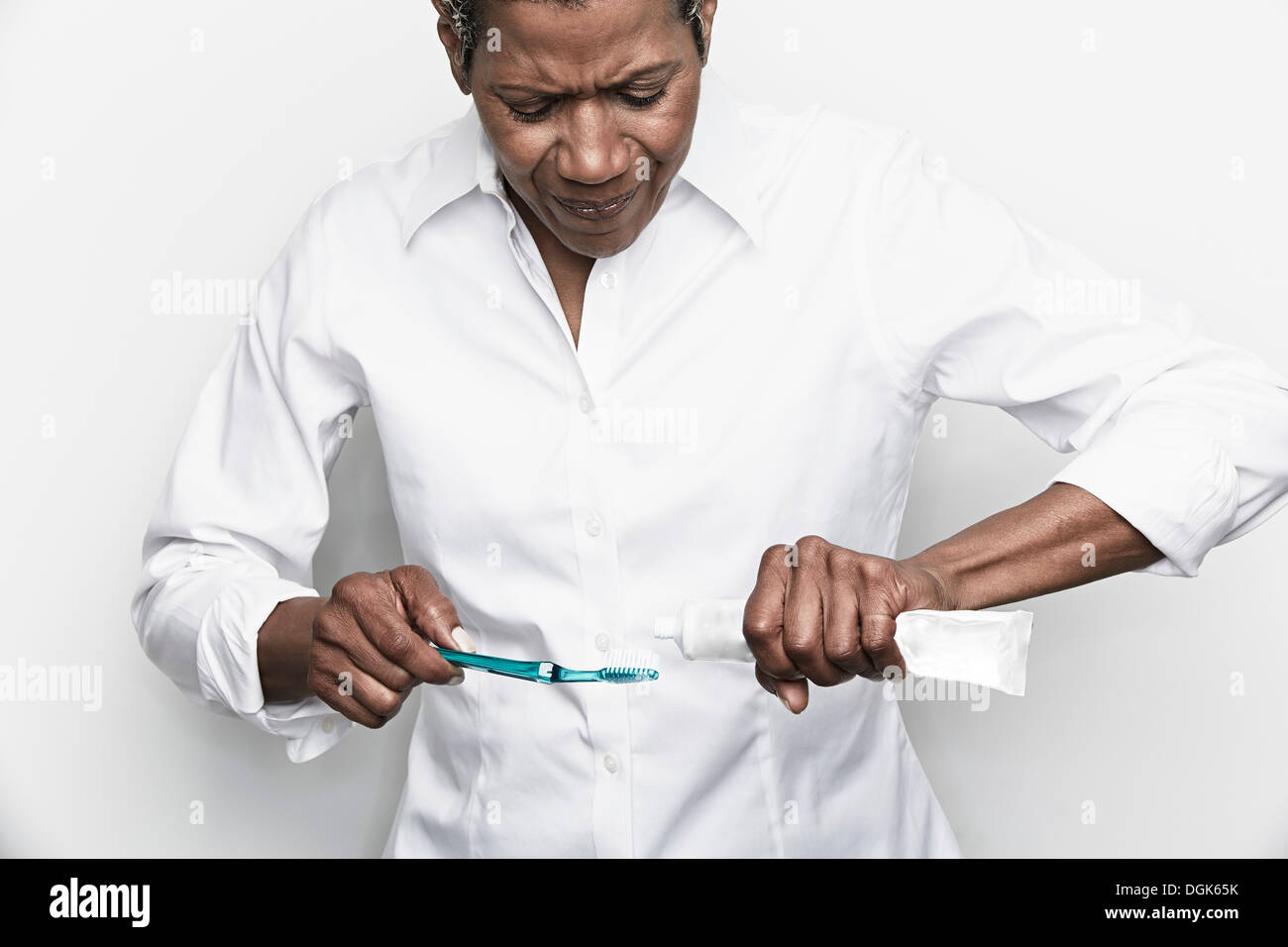 Senior woman luttant pour presser la pâte dentifrice sur une brosse à dents Banque D'Images