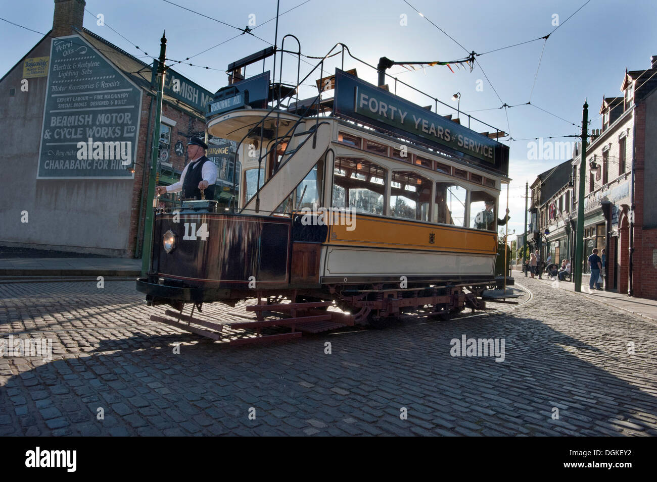 Un conducteur de tramway conduit un ancien tramway Transport préservé Newcastle Numéro 114, construit en 1901 par le biais de rues pavées de 'La Ville' dans Beamish Musée Vivant, Stanley, County Durham Banque D'Images