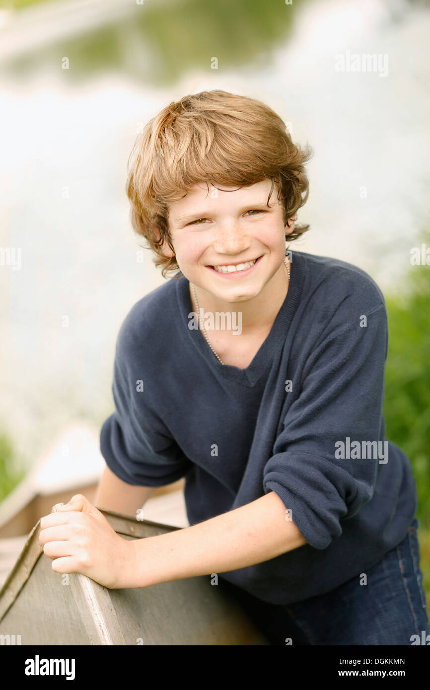 Boy (12-13) posant avec voile sur l'herbe près du lac Banque D'Images