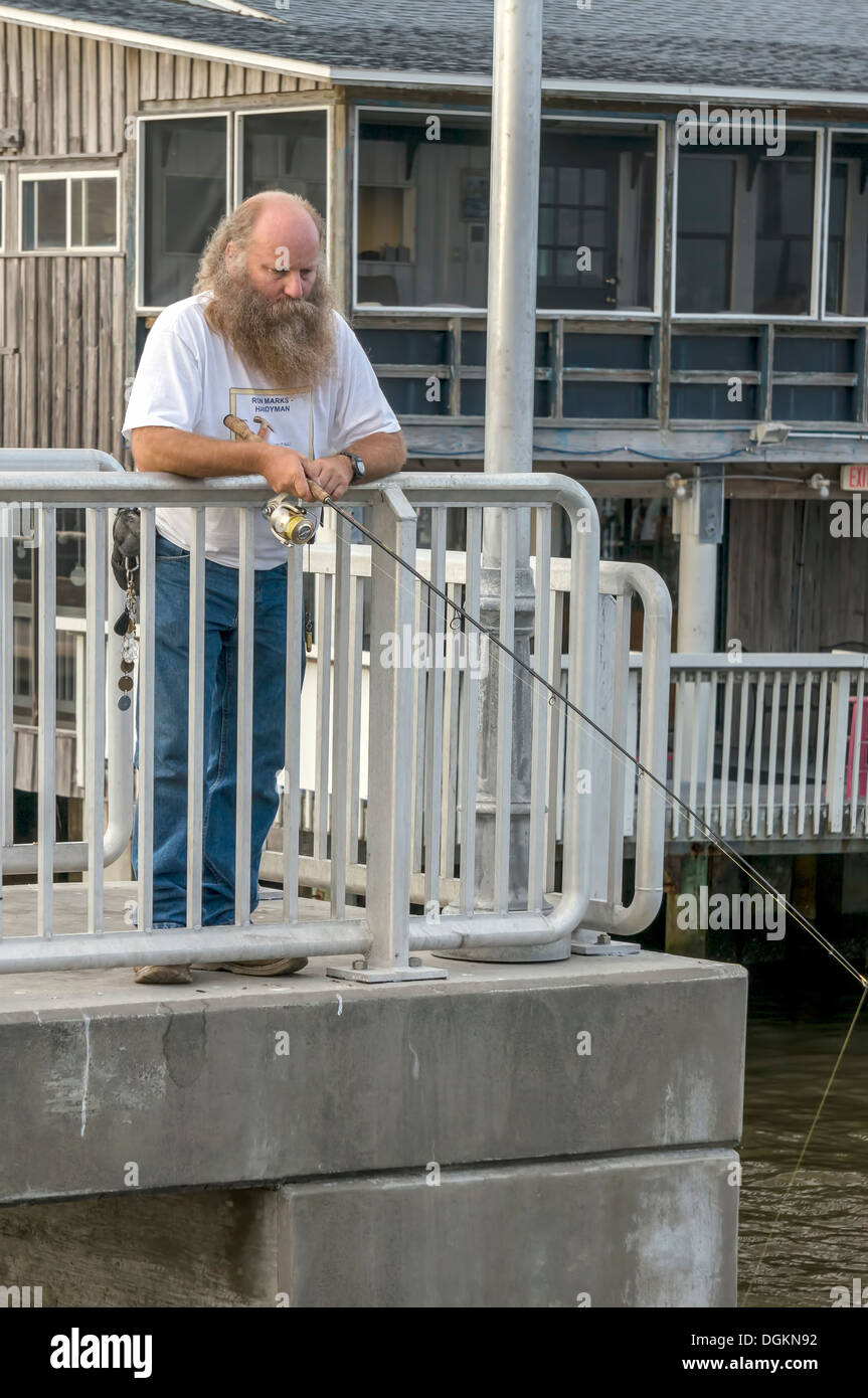Homme chauve avec barbe complète la pêche avec tige de coulée de pier. Banque D'Images