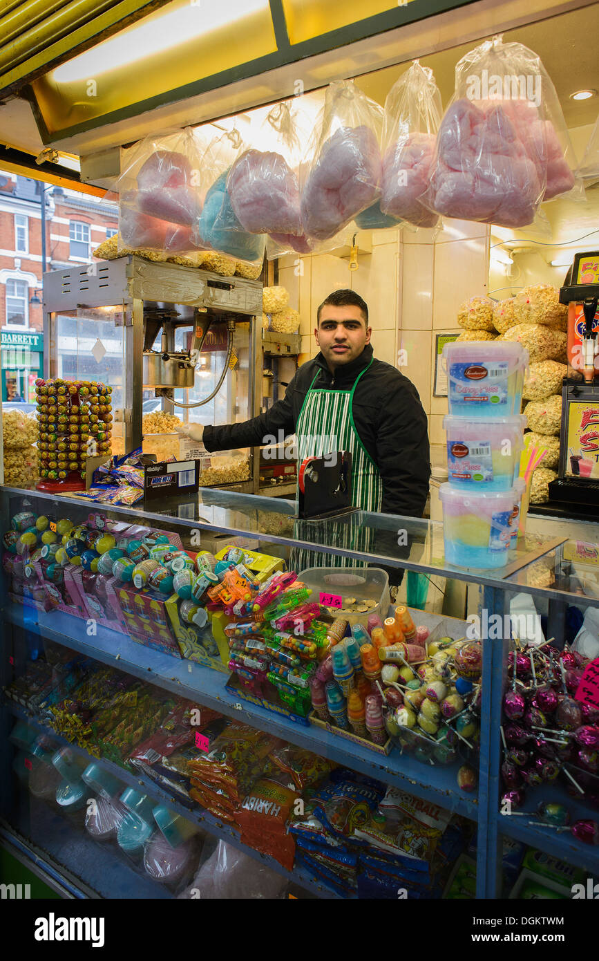 Un commerçant derrière le comptoir d'un sweet shop en marché de Brixton. Banque D'Images