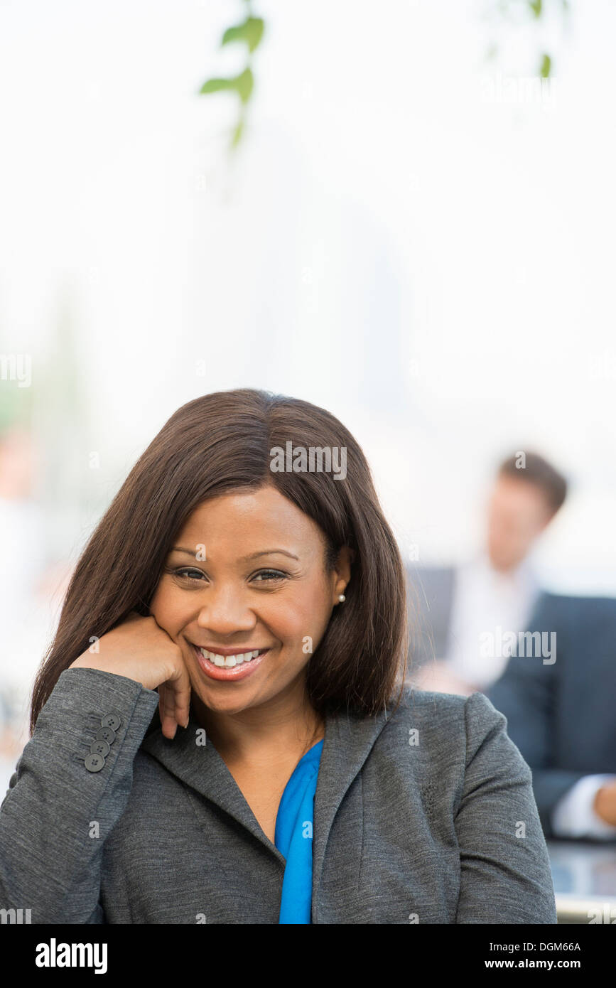 L'été. Une femme dans un costume gris avec une chemise bleu lumineux sourire. Banque D'Images