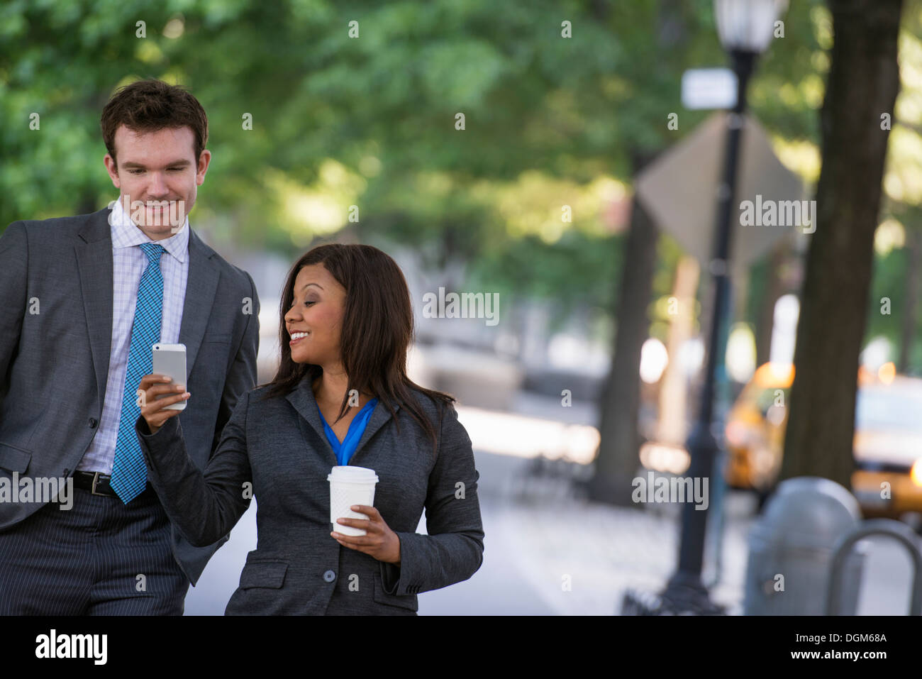 L'été. Un jeune homme en costume gris et cravate bleue marcher avec une  femme dans un costume. L'homme blanc, noir african american woman Photo  Stock - Alamy