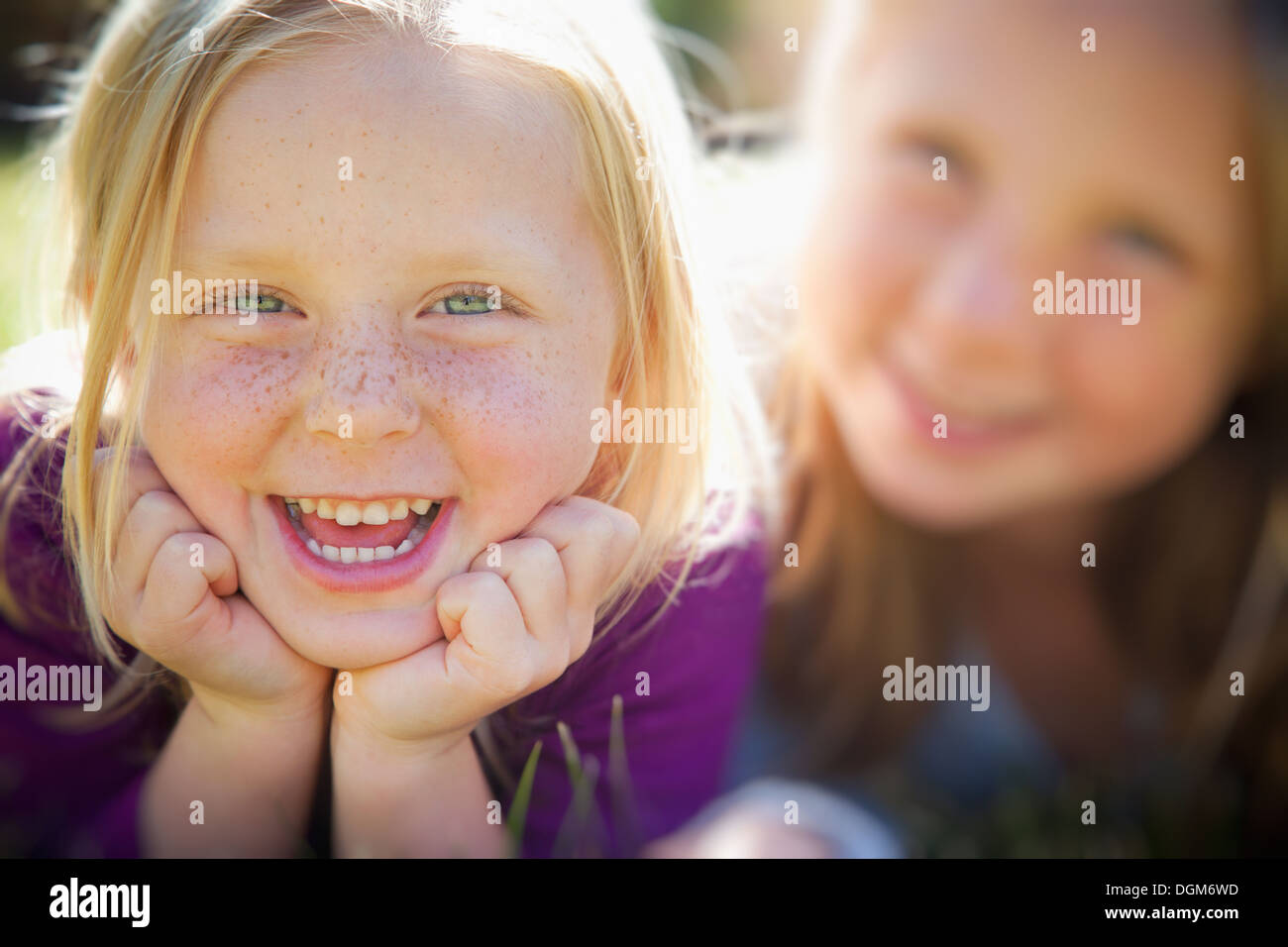 Deux jeunes filles, avec des yeux bleus et des cheveux blonds. Couché dans l'herbe. Close up. Banque D'Images
