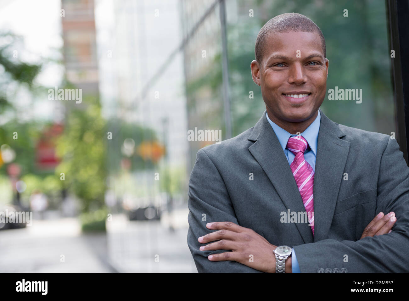 Un jeune homme dans un costume avec une chemise bleue et cravate rouge. Sur une rue de la ville. Souriant à la caméra. Banque D'Images