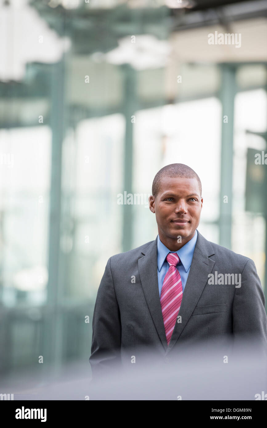Un jeune homme dans un costume avec une chemise bleue et cravate rouge. Sur une rue de la ville. Banque D'Images