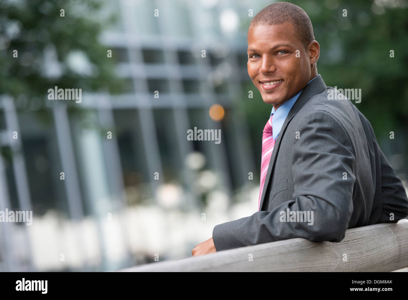 Un jeune homme dans un costume avec une chemise bleue et cravate rouge. Sur une rue de la ville. Souriant à la caméra. Banque D'Images