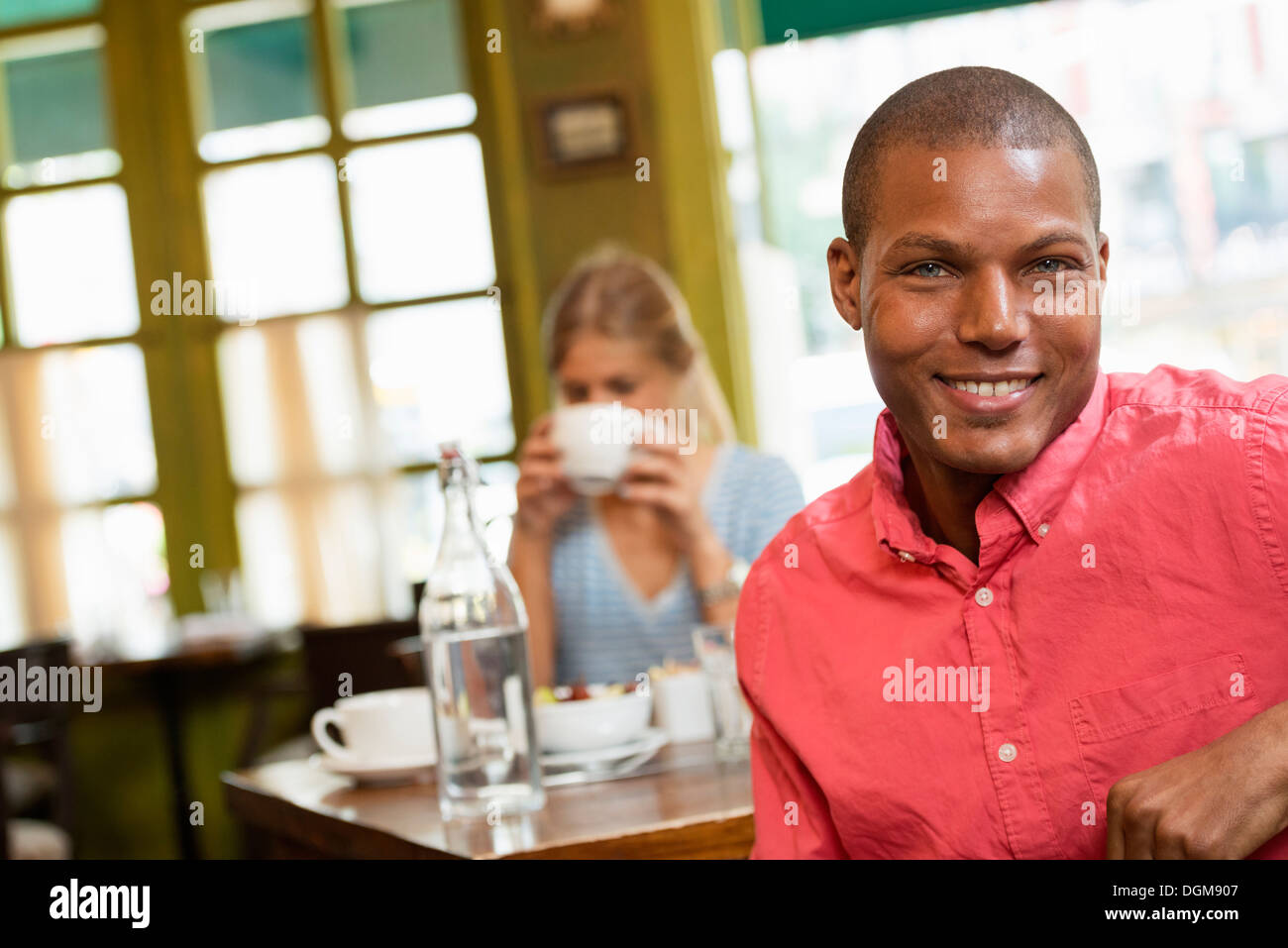 Un couple dans un café de la ville. Assis à une table. Une femme tenant une tasse de café. Banque D'Images