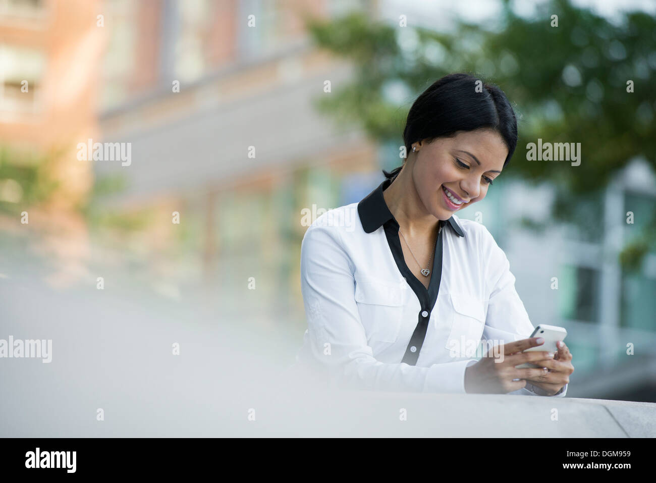 Les gens d'affaires. Une femme dans un manteau blanc contrôle de son téléphone. Banque D'Images