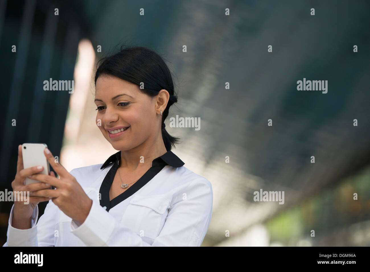 Les gens d'affaires. Une femme dans un manteau blanc contrôle de son téléphone. Banque D'Images Les gens d'affaires. Une femme dans un manteau blanc contrôle de son téléphone. Banque D'Images
