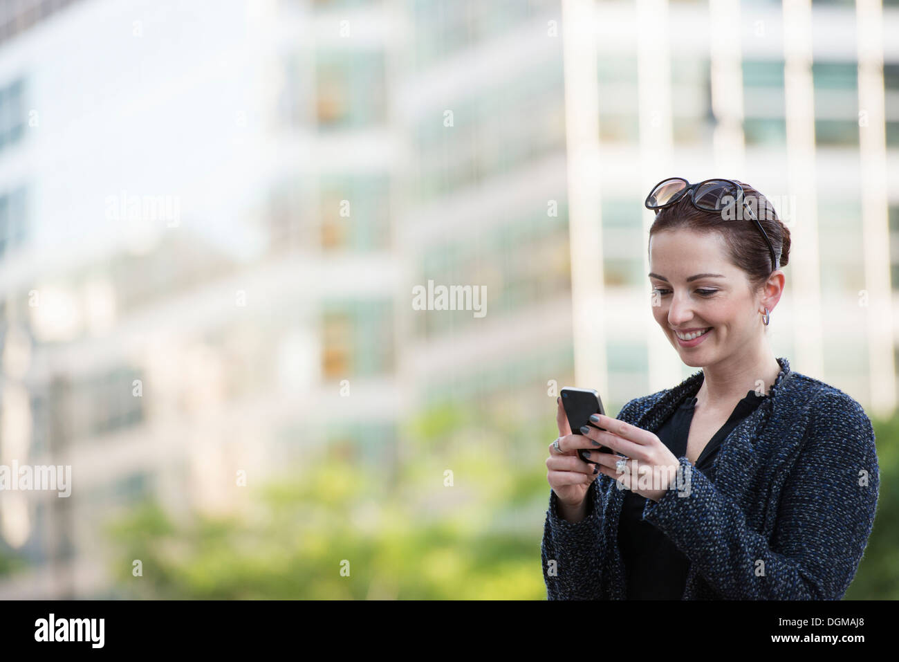 Les gens d'affaires. Une femme dans un manteau gris avec ses cheveux en place, à l'aide d'un téléphone. Banque D'Images Les gens d'affaires. Une femme dans un manteau gris avec ses cheveux en place, à l'aide d'un téléphone. Banque D'Images