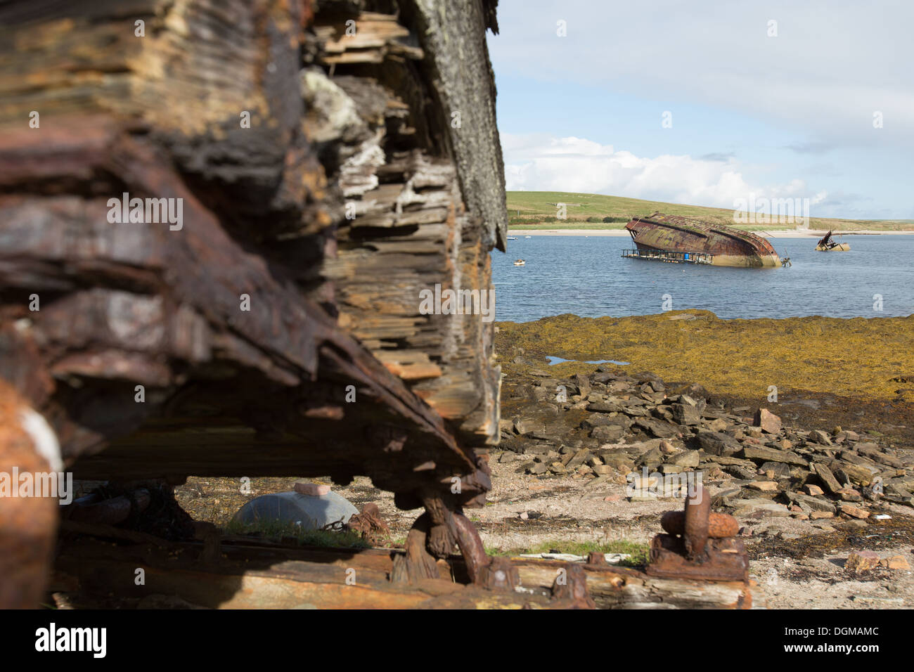 Des îles Orcades, en Écosse. Des débris sur la rive près de Barrière Churchill numéro 3 avec un blockship dans l'arrière-plan. Banque D'Images