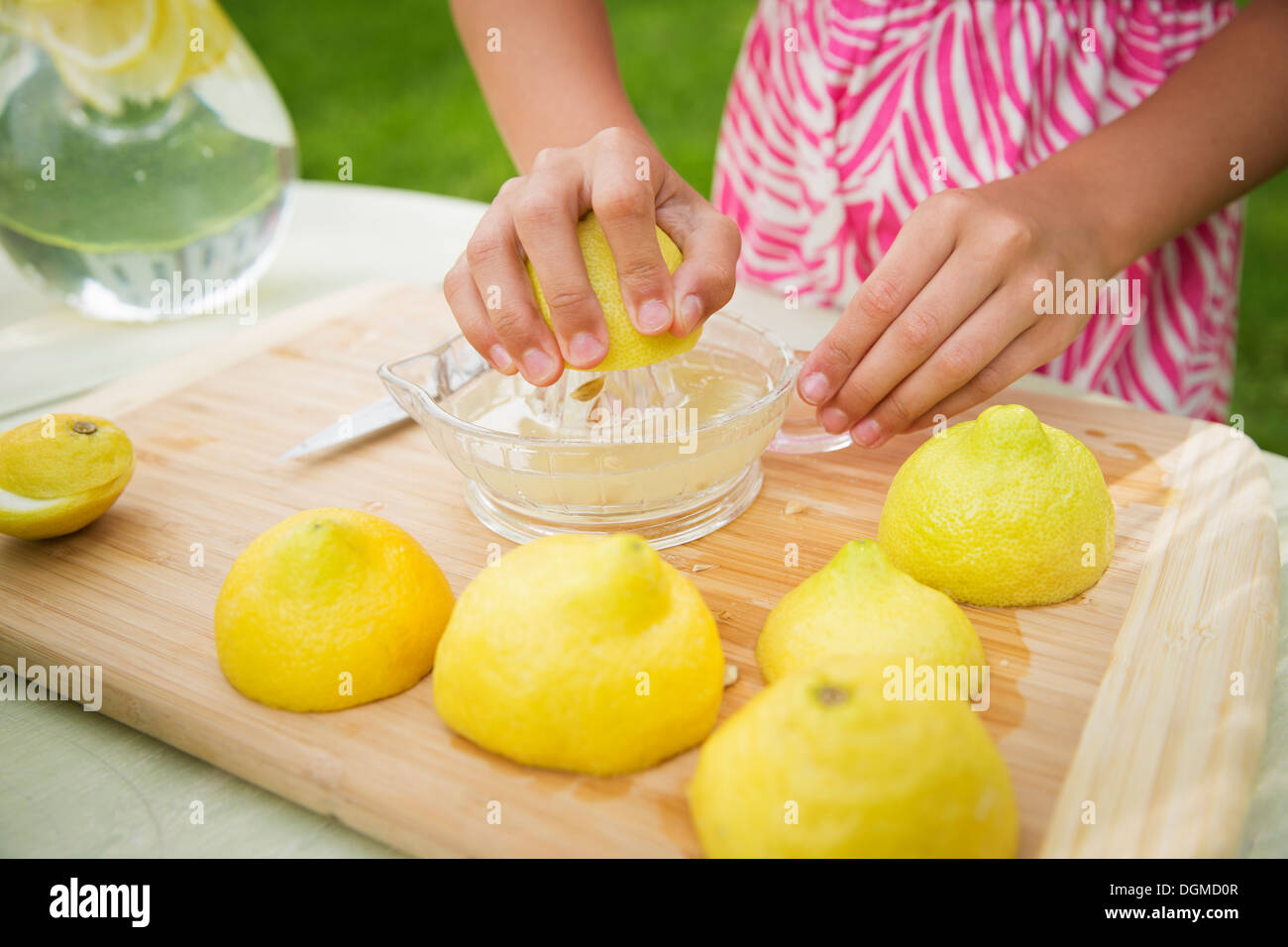 Une réunion de famille d'été dans une ferme. Une fille de trancher et faire un jus de citrons, faire de la limonade. Banque D'Images