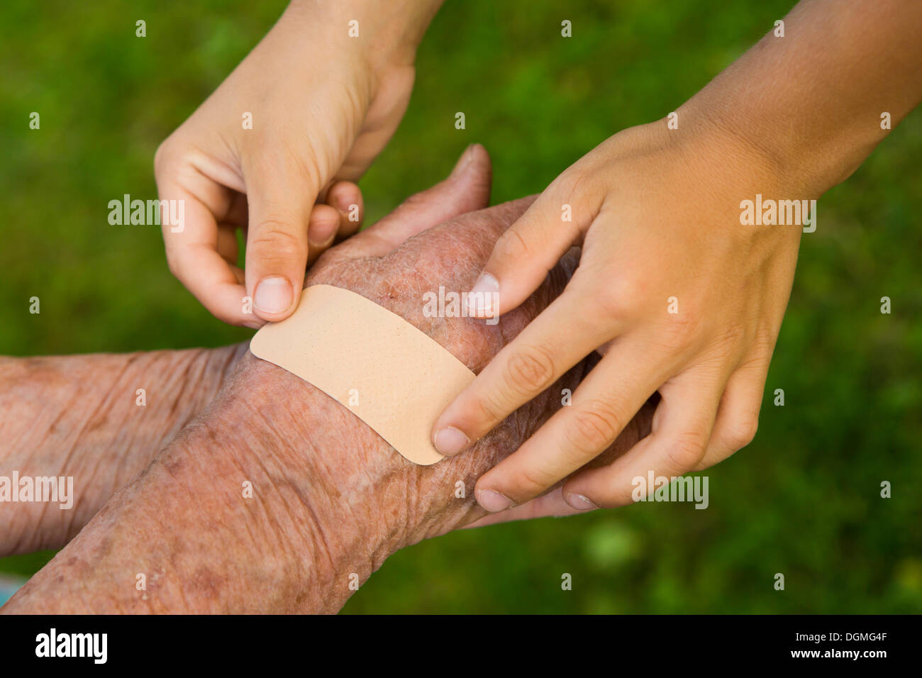 Enfant de mettre un plâtre sur la main d'une femme âgée. Banque D'Images